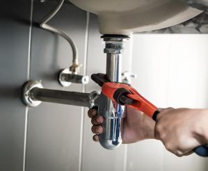 hand fixing a pipe under sink