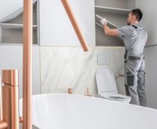 person in large bathroom putting up shelf