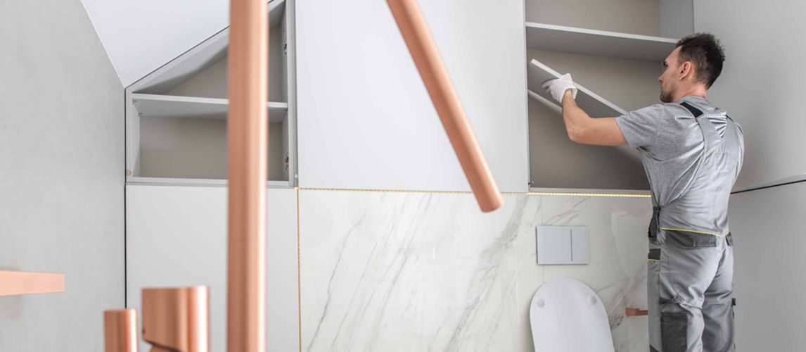 person in large bathroom putting up shelves