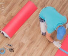 A close-up of worker doing home flooring renovation with vinyl flooring