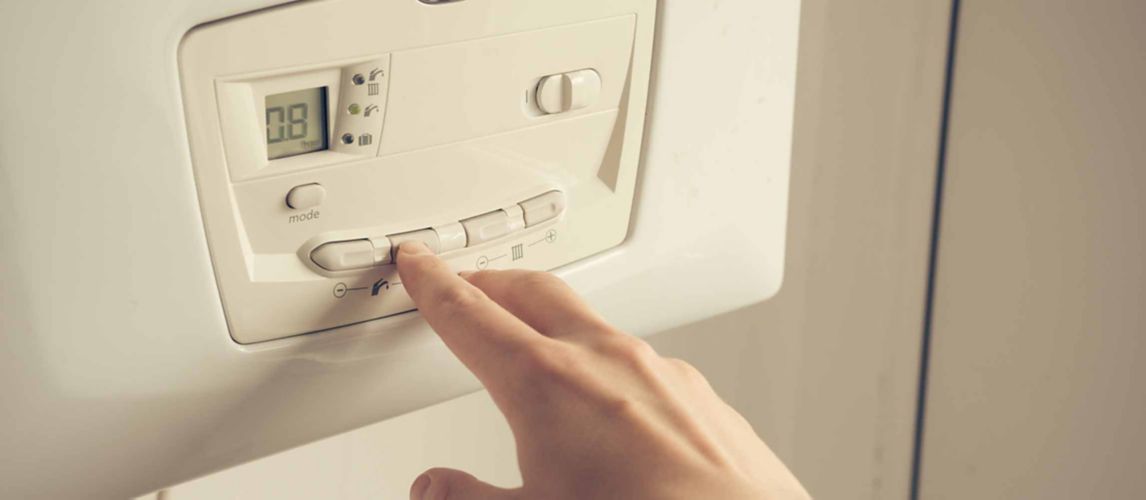 Person adjusting the control panel on a boiler