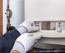 person touching boiler controls