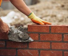 Bricklayer using a line and chalk to build a brick wall