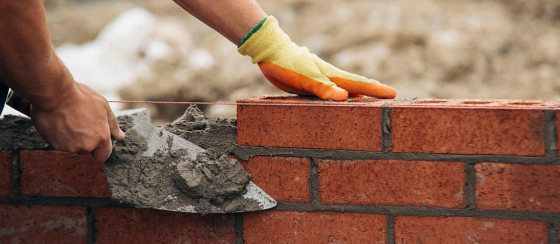 Bricklayer using a line and chalk to build a brick wall