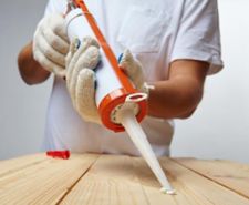 man wearing glove caulking wood