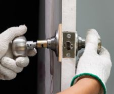 Man’s hand in work gloves repairing a broken door knob