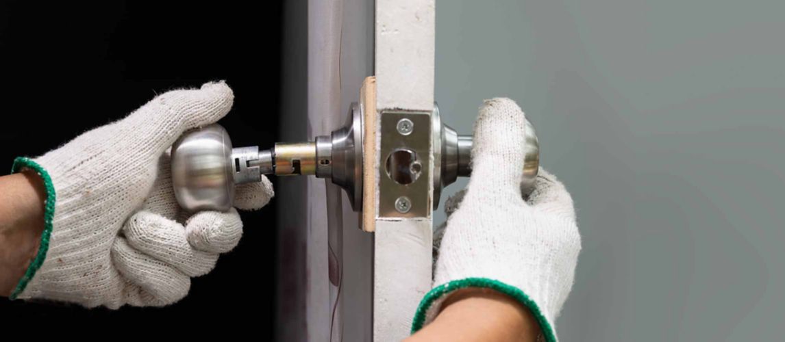 Man’s hand in work gloves repairing a broken door knob