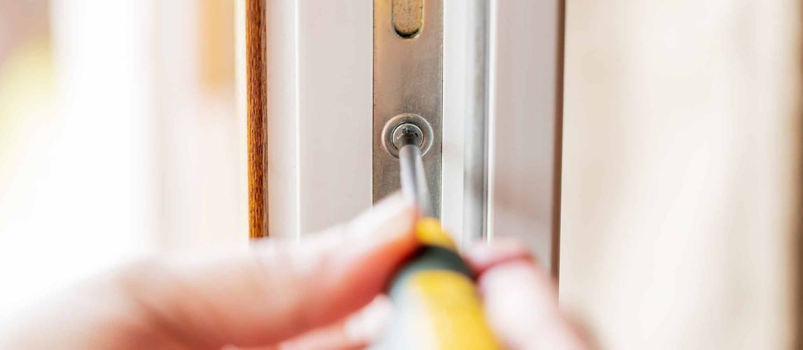 Person using a cordless drill to change a lock on a uPVC door