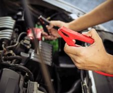 Person holding jump leads about to connect a car battery to a car battery charger