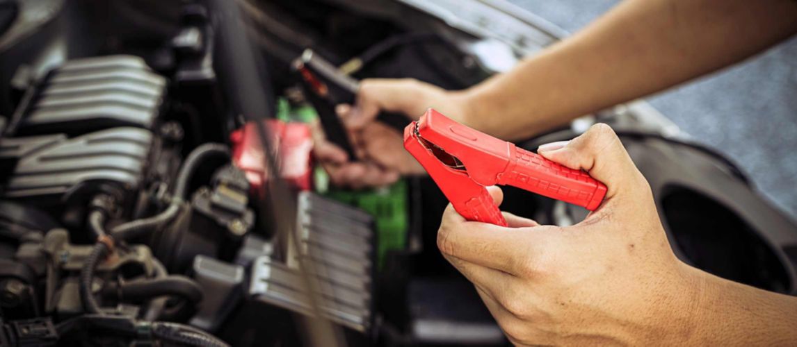 Person holding jump leads about to connect a car battery to a car battery charger