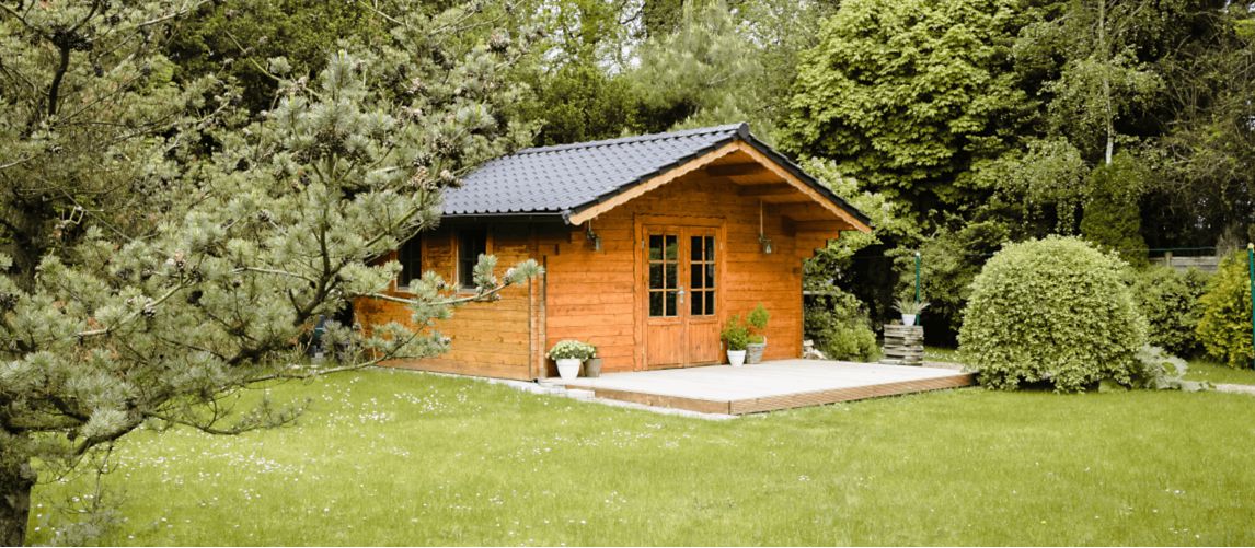 Wooden shed on garden lawn with trees behind it