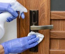 Gloved hands cleaning a brass door handle
