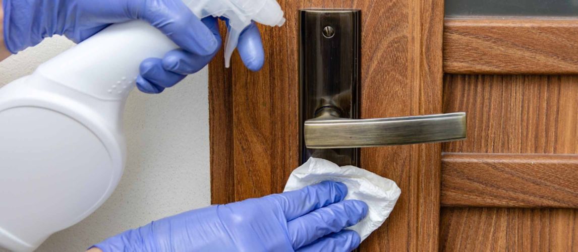 Gloved hands cleaning a brass door handle