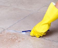 Floor tile grout being cleaned with a solution and toothbrush