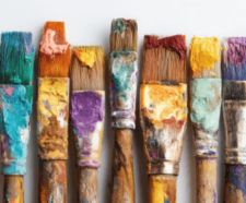 9 paint brushes all covered in different colours of paint