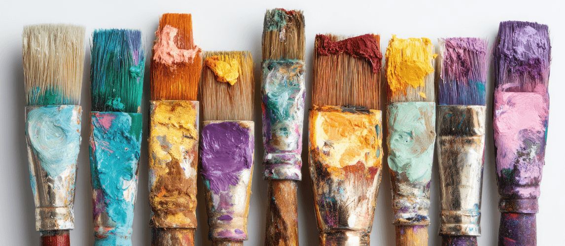 9 paint brushes all covered in different colours of paint