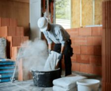 Bricklayer putting cement in tub at construction site
