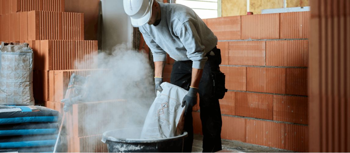 Bricklayer putting cement in tub at construction site