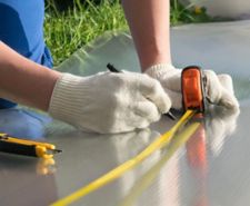 person wearing gloves marking with a pen using tape measure