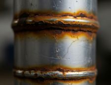 Close-up of rusted weld seams on a metal pipe showing corrosion and cracking.
