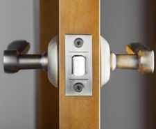 Side on view of a door latch installed with standard door handles