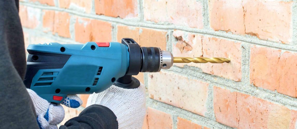 person drilling into brick tile on wall