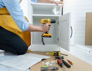 person drilling into cabinet