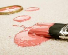 Pink paint spilled on cream coloured carpet with brush.