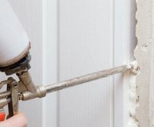 person filling in a gap in building work with expanding foam