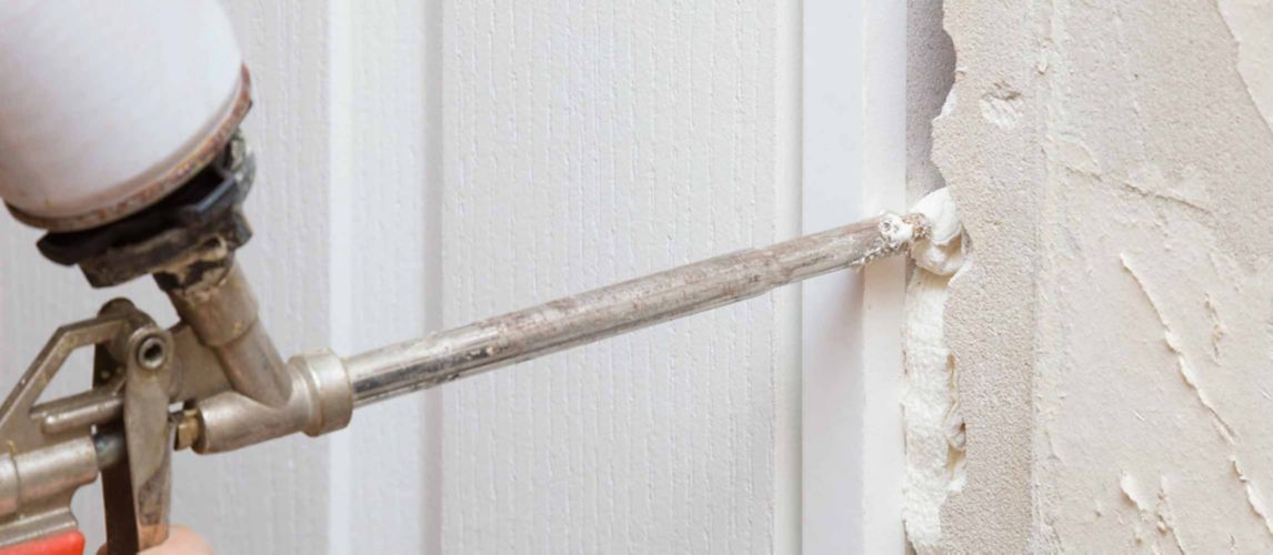 person filling in a gap in building work with expanding foam