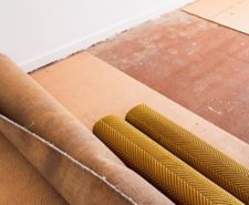Ripped up and rolled up carpet and floor underlay revealing floorboard in home interior renovation project