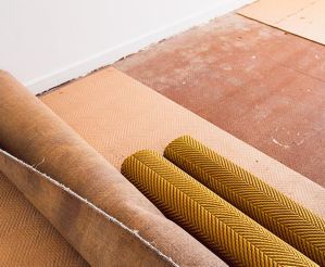 Ripped up and rolled up carpet and floor underlay revealing floorboard in home interior renovation project