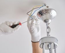 Person installing a light fitting on a ceiling