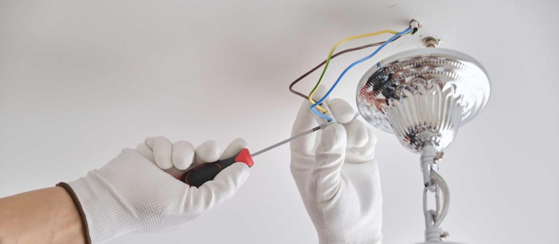 Person installing a light fitting on a ceiling