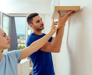 young couple putting up a floating shelf