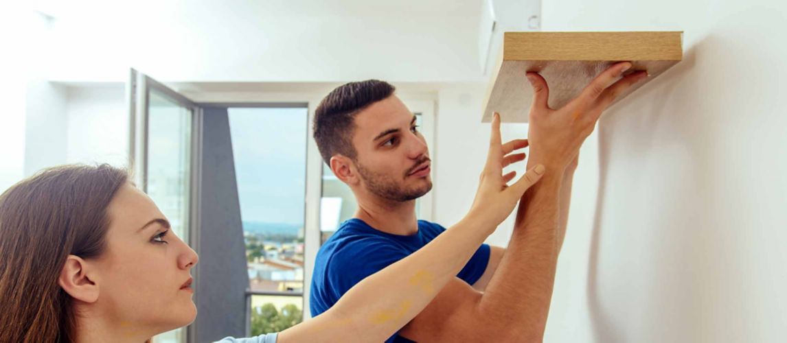 Young couple putting up a floating shelf