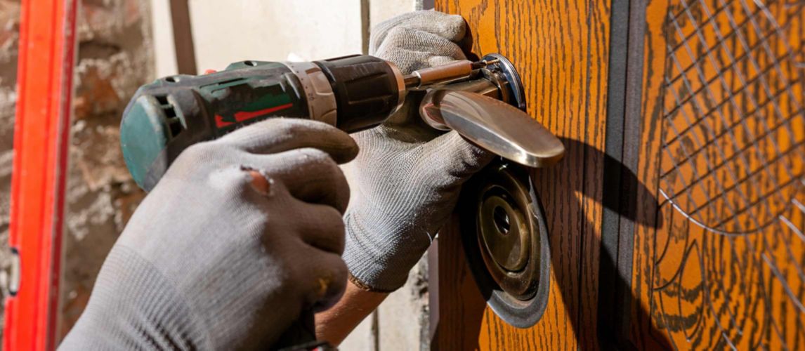 Carpenter using a combi drill whilst replacing a front door lock 