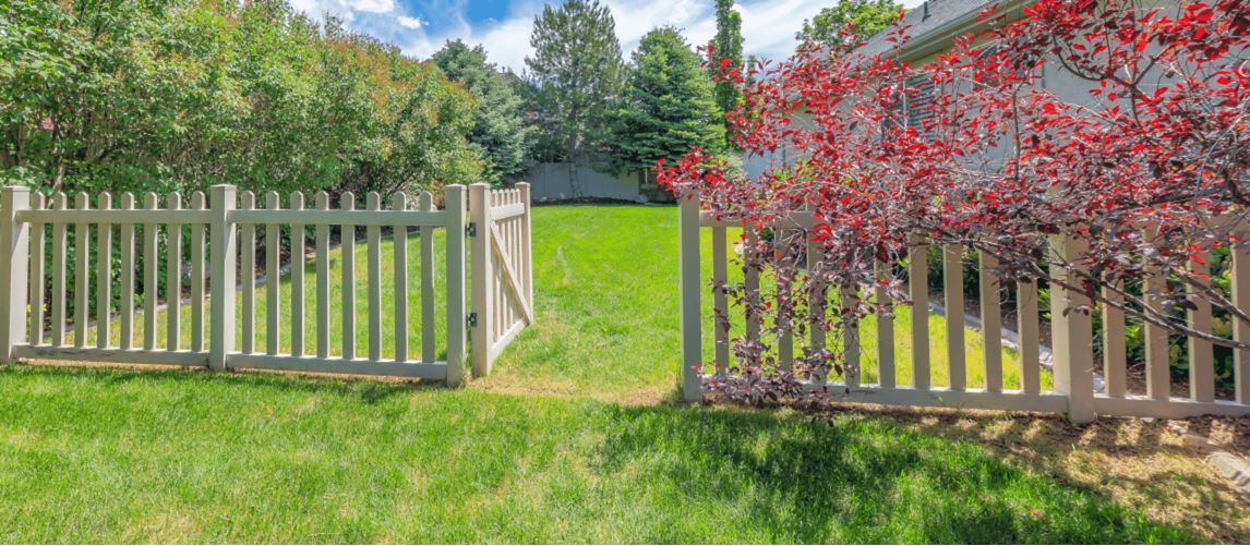 a wooden garden gate and fence on a green lawn