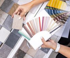Woman architect designer selects epoxy grout colour for ceramic tiles, comparing colour samples
