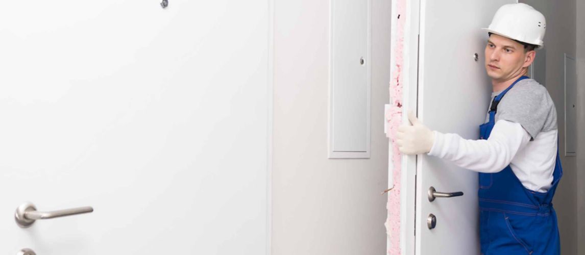 Man carrying an old door after removing it in preparation to hang a new door