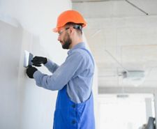 Man smoothing a plastered wall with a filling knife
