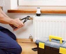 a person using a wrench remove a radiator valve