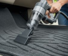 close up of handheld vacuum being used to clean car mats