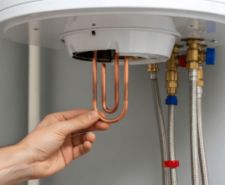 Professional plumber installing new boiler immersion heater element.