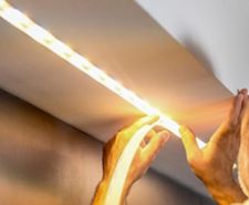 Man installing LED strip lights in a ceiling