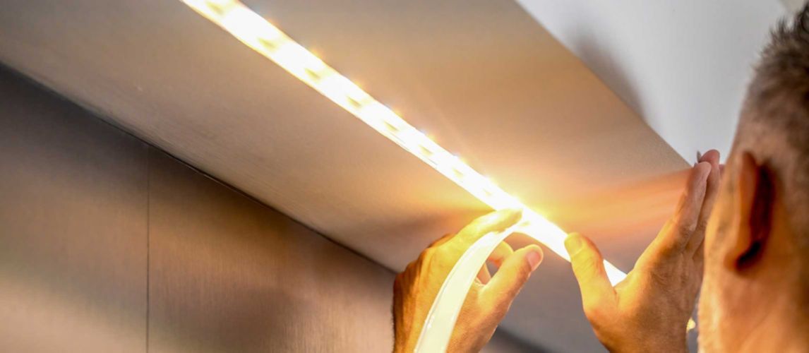Man installing LED strip lights in a ceiling