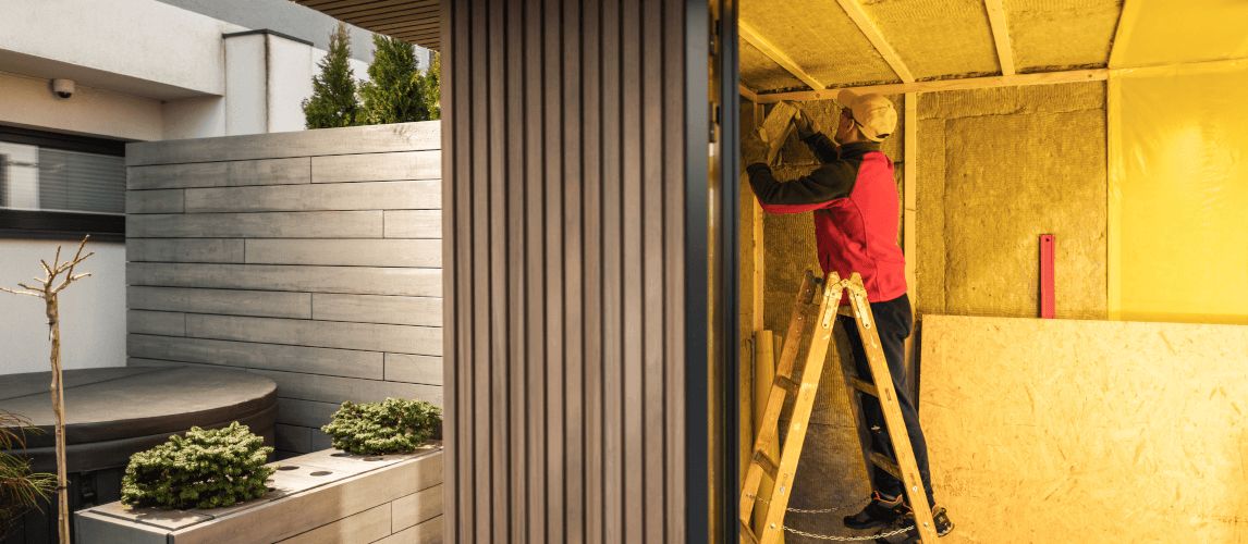 Man Insulating Newly Built Garden Shed with Mineral Wool