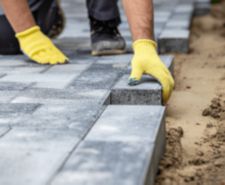 a worker laying bricks for a patio