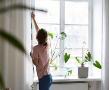 Rear view of a woman measuring curtains on wall at home