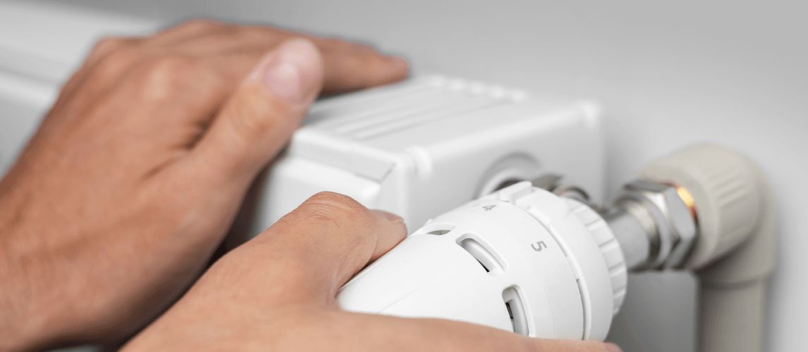 close up of Hand Adjusting Heating Thermostat, one hand operates the temperature controller radiator